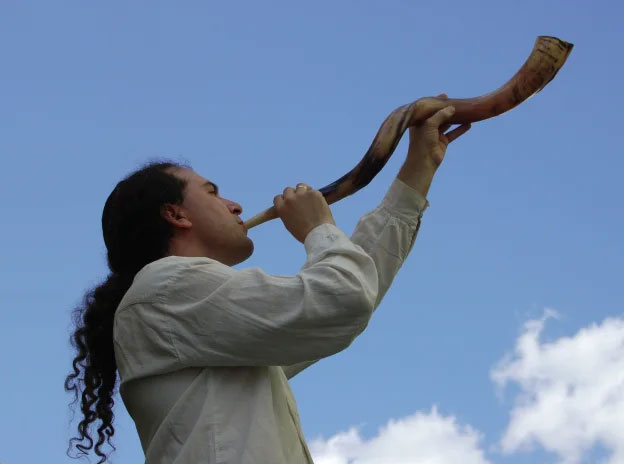 Reb Josh blowing a large spiral shofar