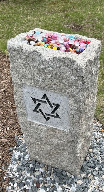 A granite post topped by a basin of polished colorful stones.